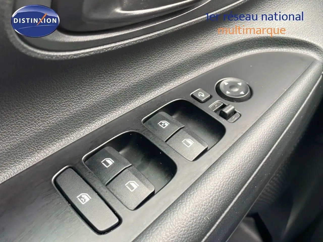 Gros plan sur les commandes des vitres électriques côté conducteur d'une Hyundai i20 2025 finition Klass noire.