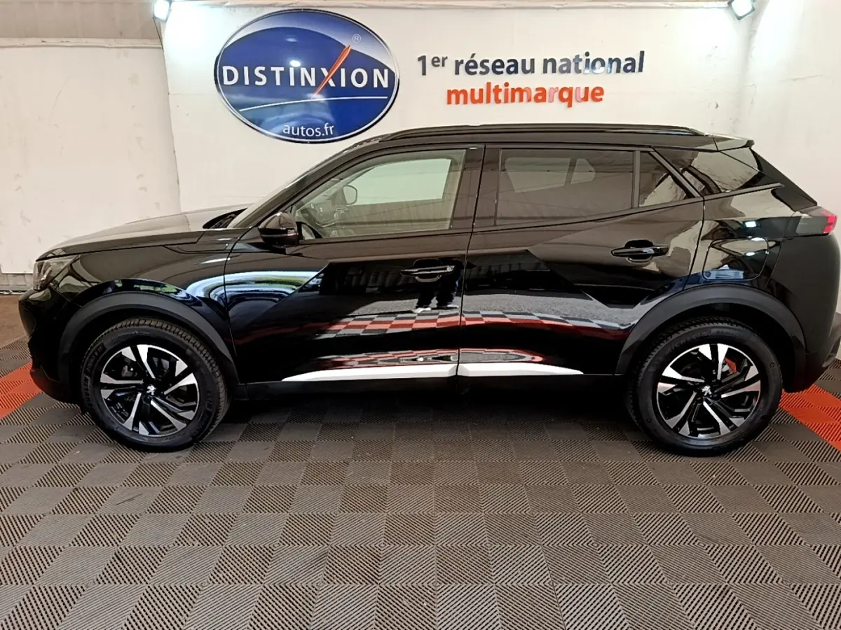 Profil côté gauche d’un Peugeot 2008 noir 2021 avec jantes noires et détails chromés, stationné en intérieur.