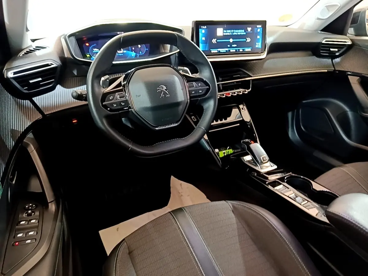 Vue intérieure de la Peugeot 2008 noire, tableau de bord moderne avec écran tactile 10 pouces et volant cuir multifonctions.