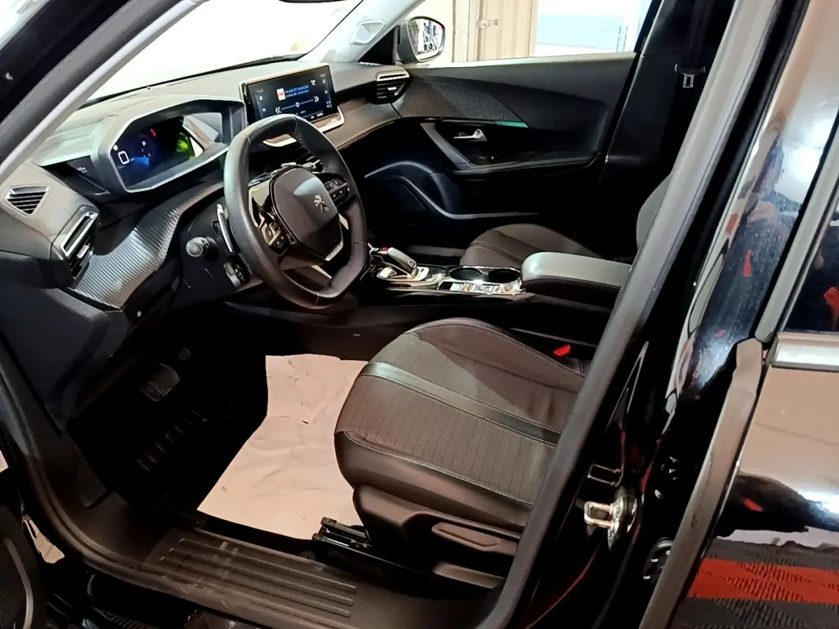 Intérieur avant droit du Peugeot 2008 noir 2021, volant cuir, écran tactile 10 pouces et sièges tissu gris.