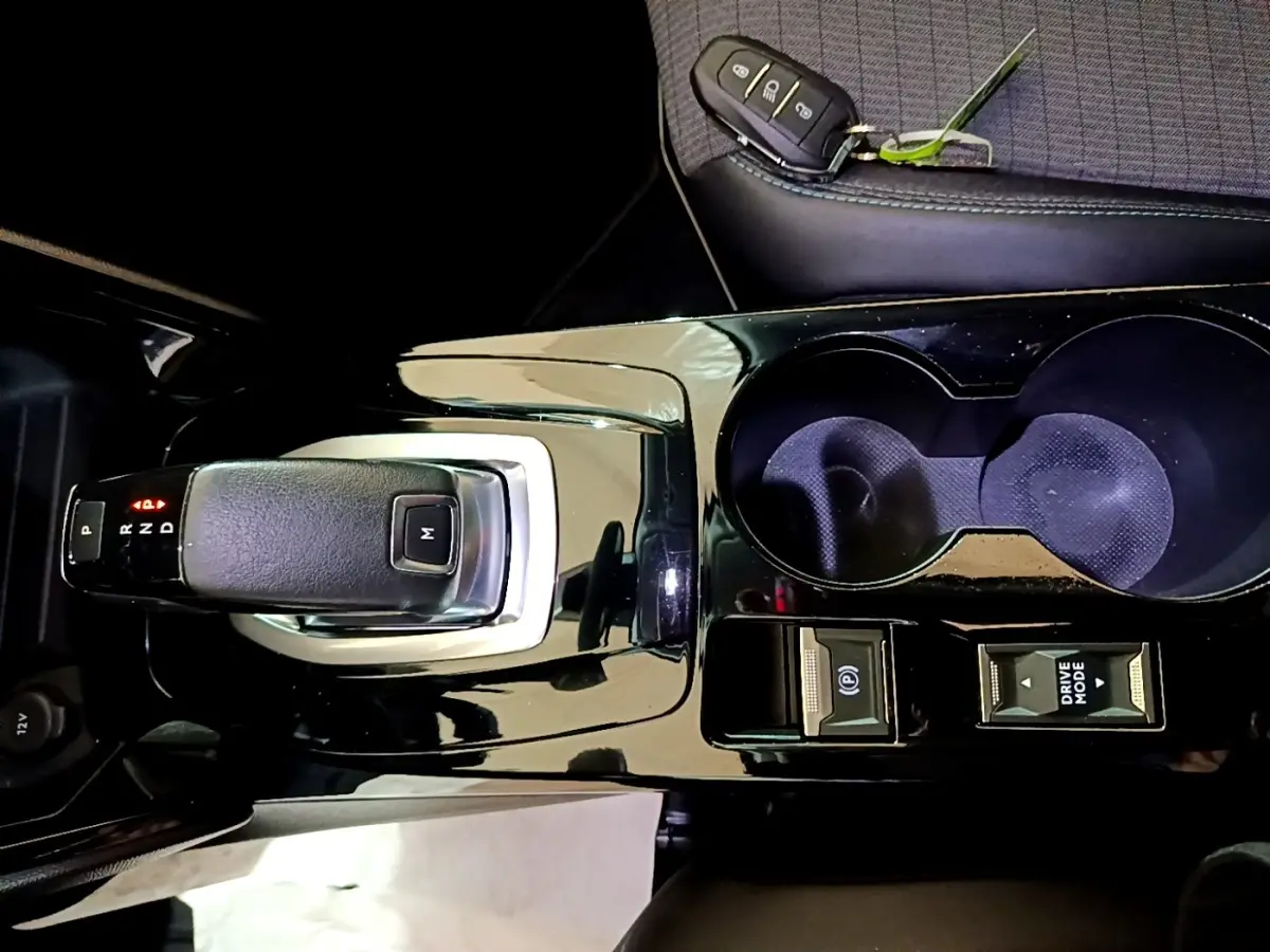Vue rapprochée de la console centrale noire brillante de la Peugeot 2008 avec levier de boîte auto et porte-clés posé.