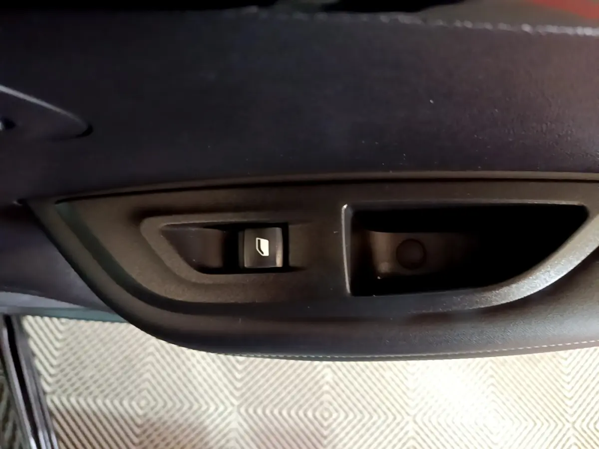 Gros plan sur la commande de lève-vitre côté porte intérieure d’une Peugeot 2008 noire, version 2021.