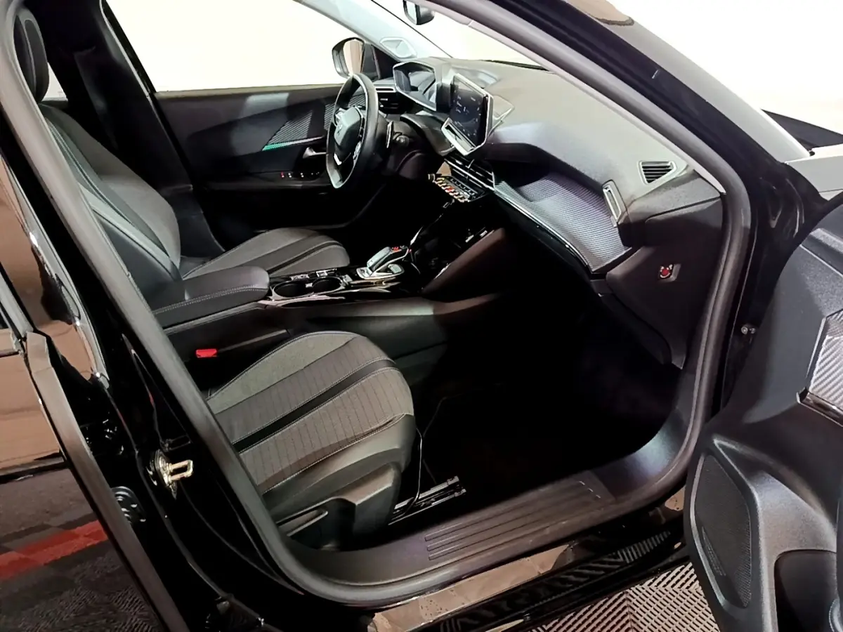 Intérieur avant droit du Peugeot 2008 noir, mettant en valeur sièges, tableau de bord et écran tactile central.