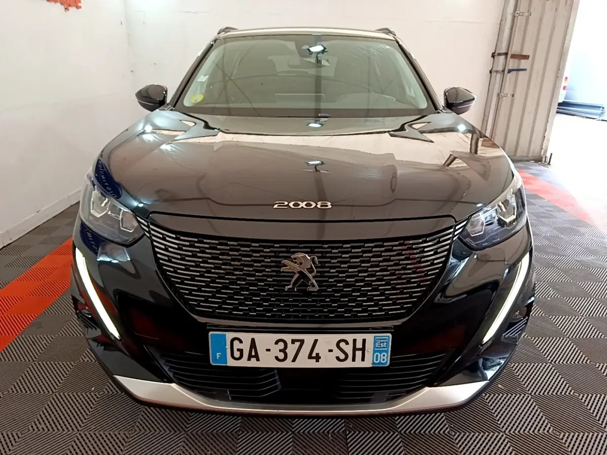 Vue avant d'un Peugeot 2008 noir avec calandre distinctive et feux LED en forme de griffes allumés.