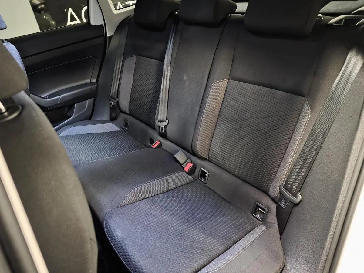 Vue intérieure de la banquette arrière en tissu noir et gris du Volkswagen Taigo 2024, avec ceintures de sécurité visibles.