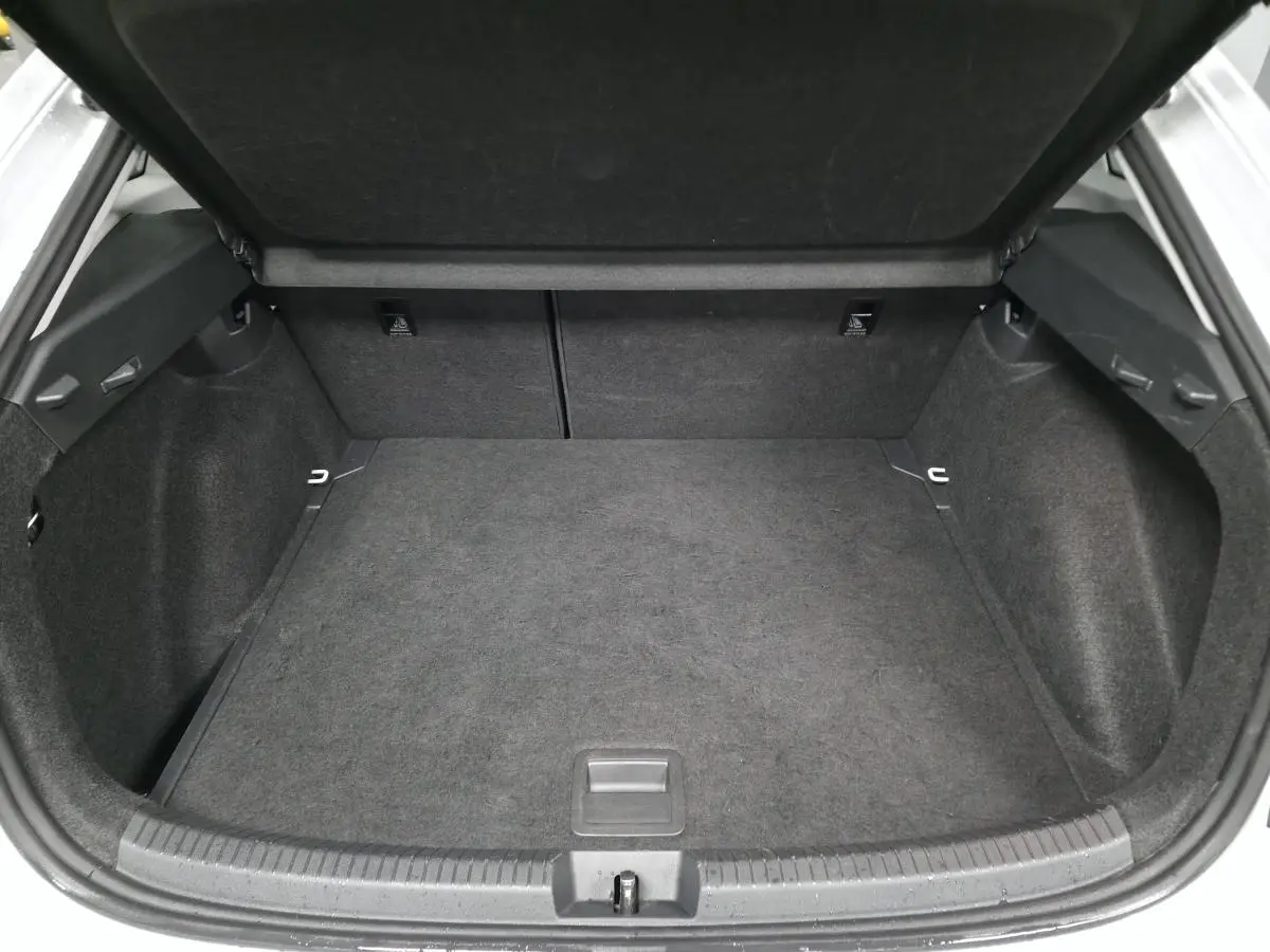 Coffre ouvert du Volkswagen Taigo blanc, vue arrière montrant un espace de chargement propre et spacieux.