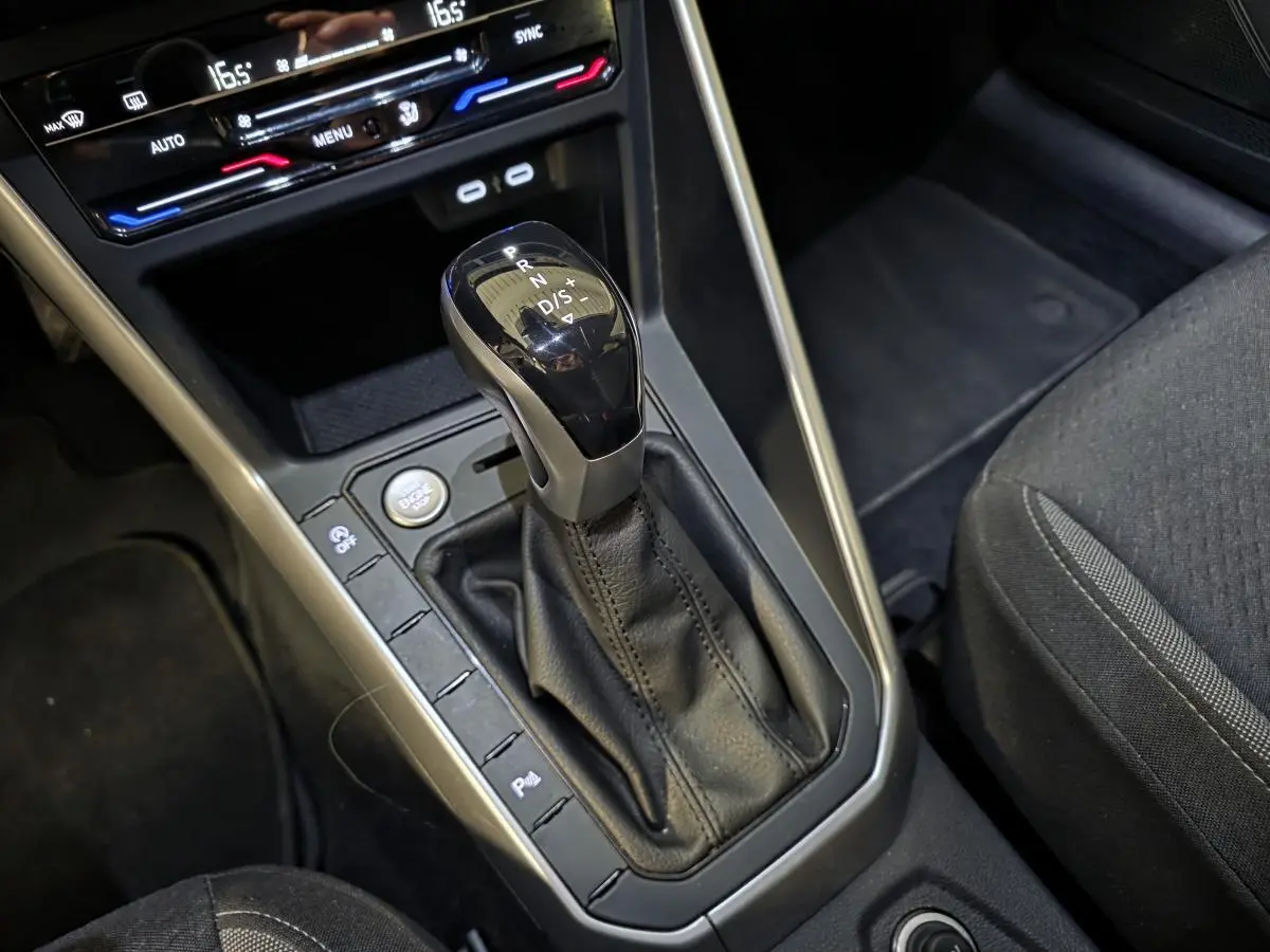 Le levier de vitesses automatique noir et argenté de la Volkswagen Taigo 2024, avec console centrale et siège tissu gris.