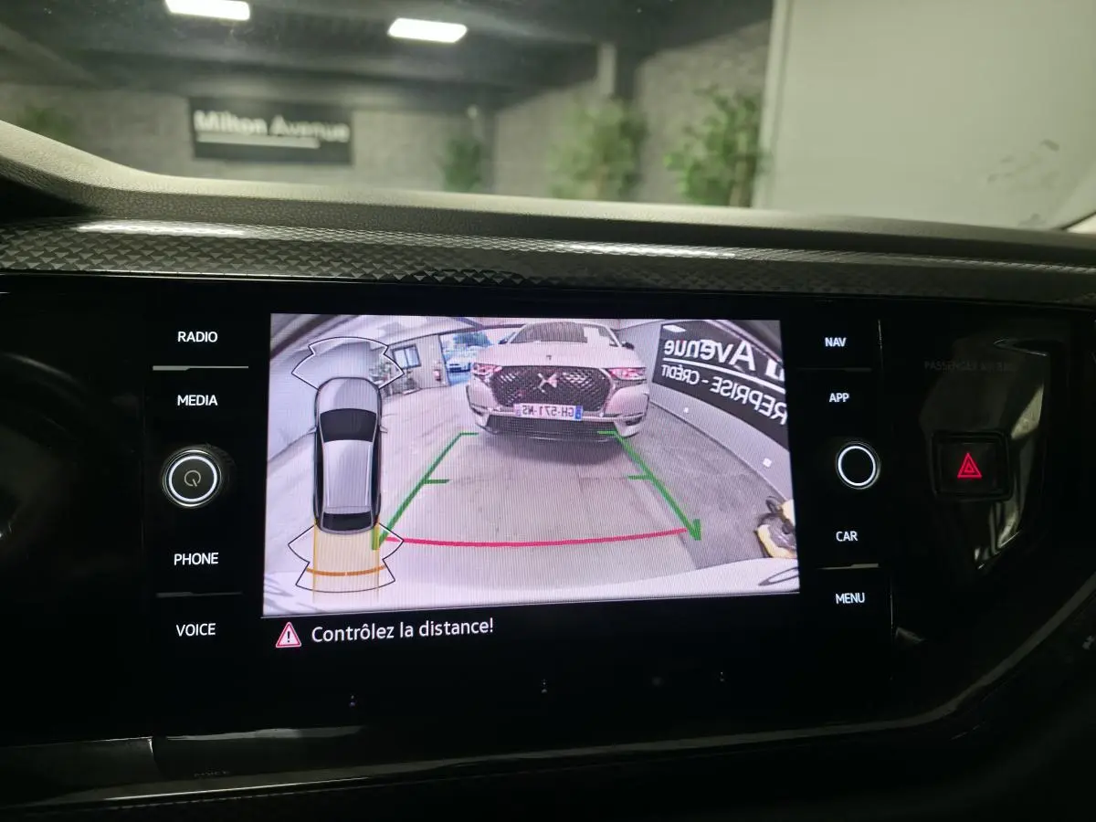 Écran tactile intérieur montrant la caméra de recul avec vue arrière d'un SUV blanc en garage.