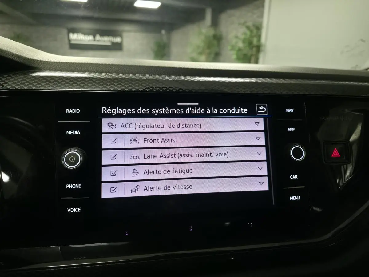 Écran tactile intérieur du Volkswagen Taigo blanc montrant les réglages d'aide à la conduite.