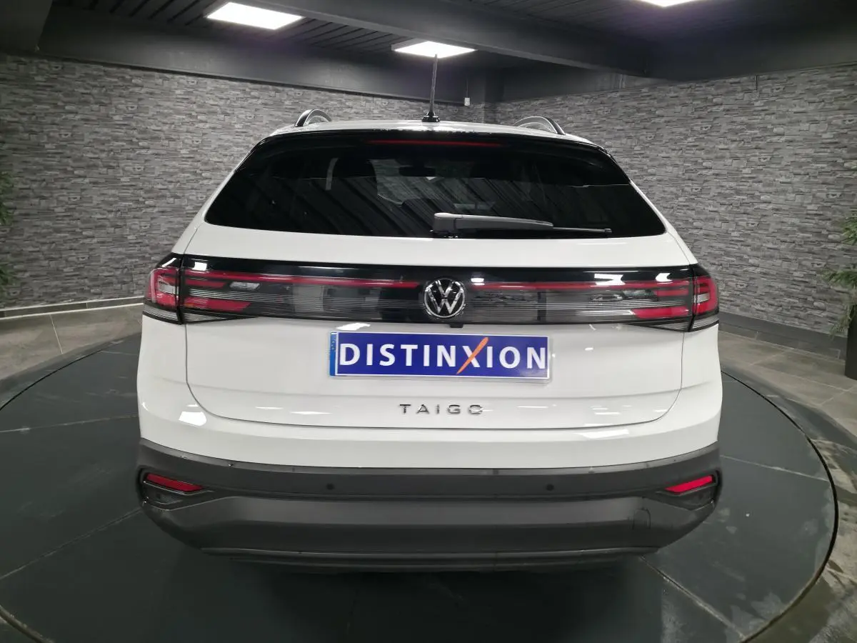 Vue arrière d'un Volkswagen Taigo blanc avec feux arrière reliés par une bande noire brillante.