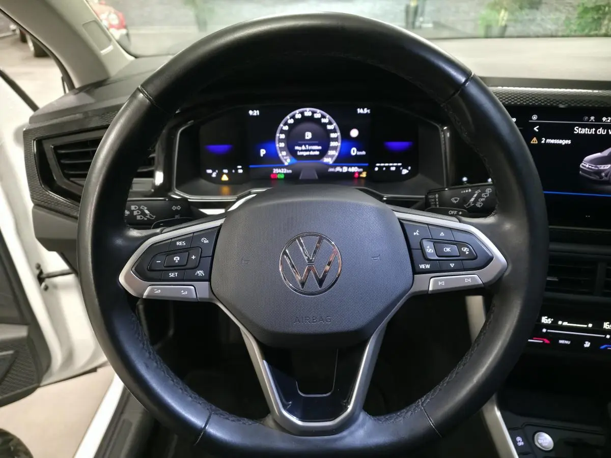 Vue rapprochée du volant multifonctions en cuir d'une Volkswagen Taigo 2024 avec tableau de bord numérique allumé.