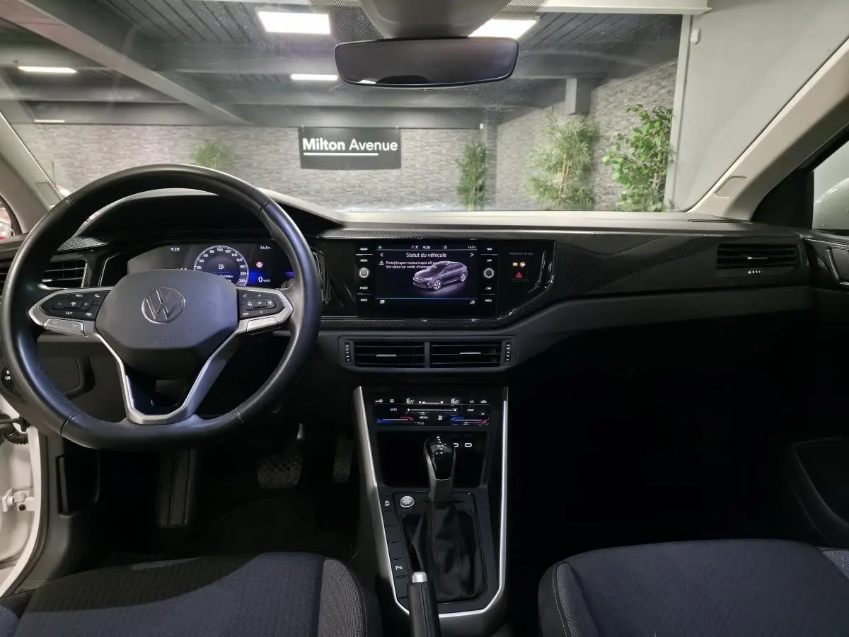 Vue intérieure frontale du tableau de bord et volant cuir noir d'un Volkswagen Taigo 2024 avec écran tactile et levier de boîte auto