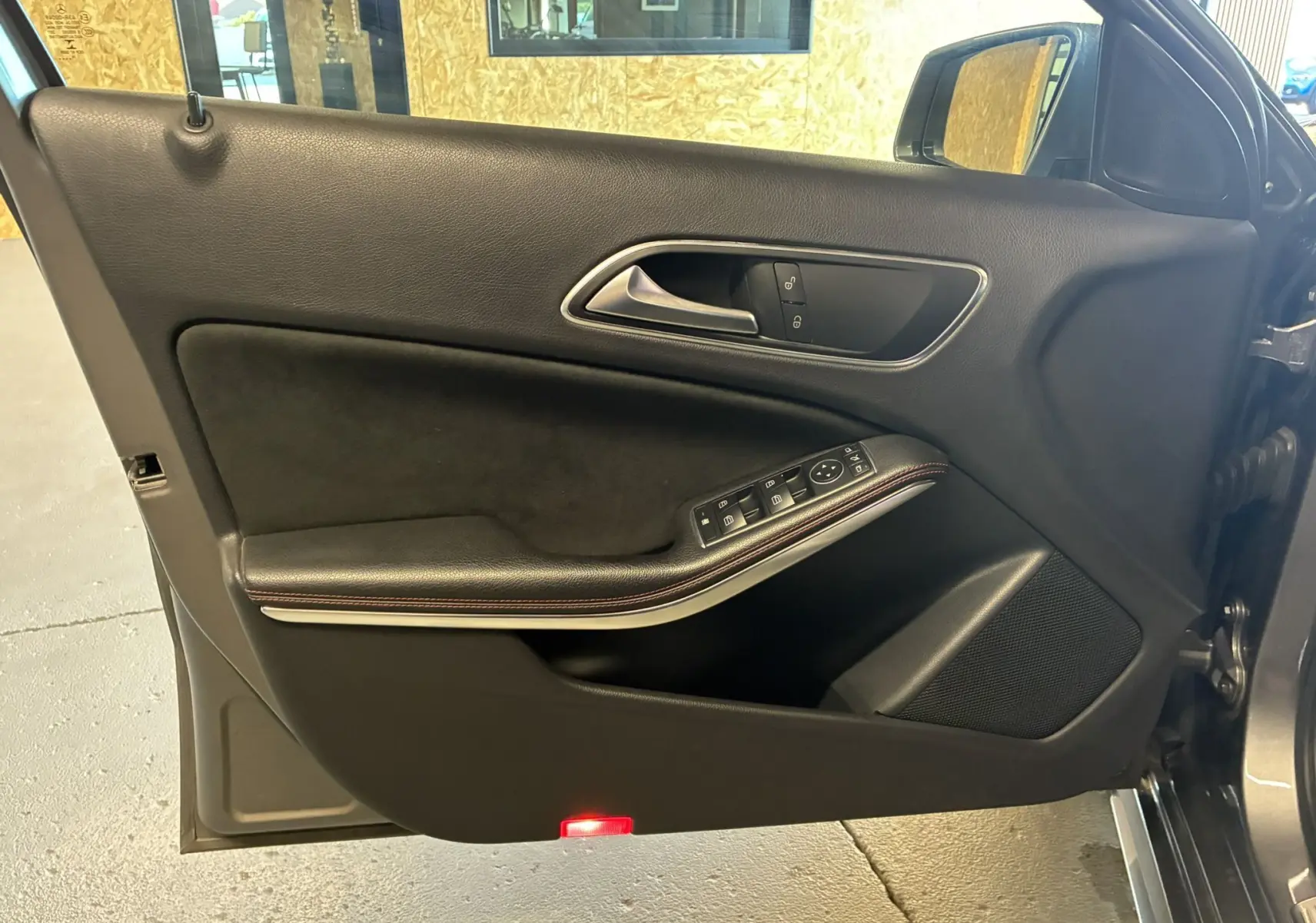 Intérieur côté gauche de la porte avant d'une Mercedes Classe A 250 AMG Sport gris, avec garniture noire et commandes électriques.