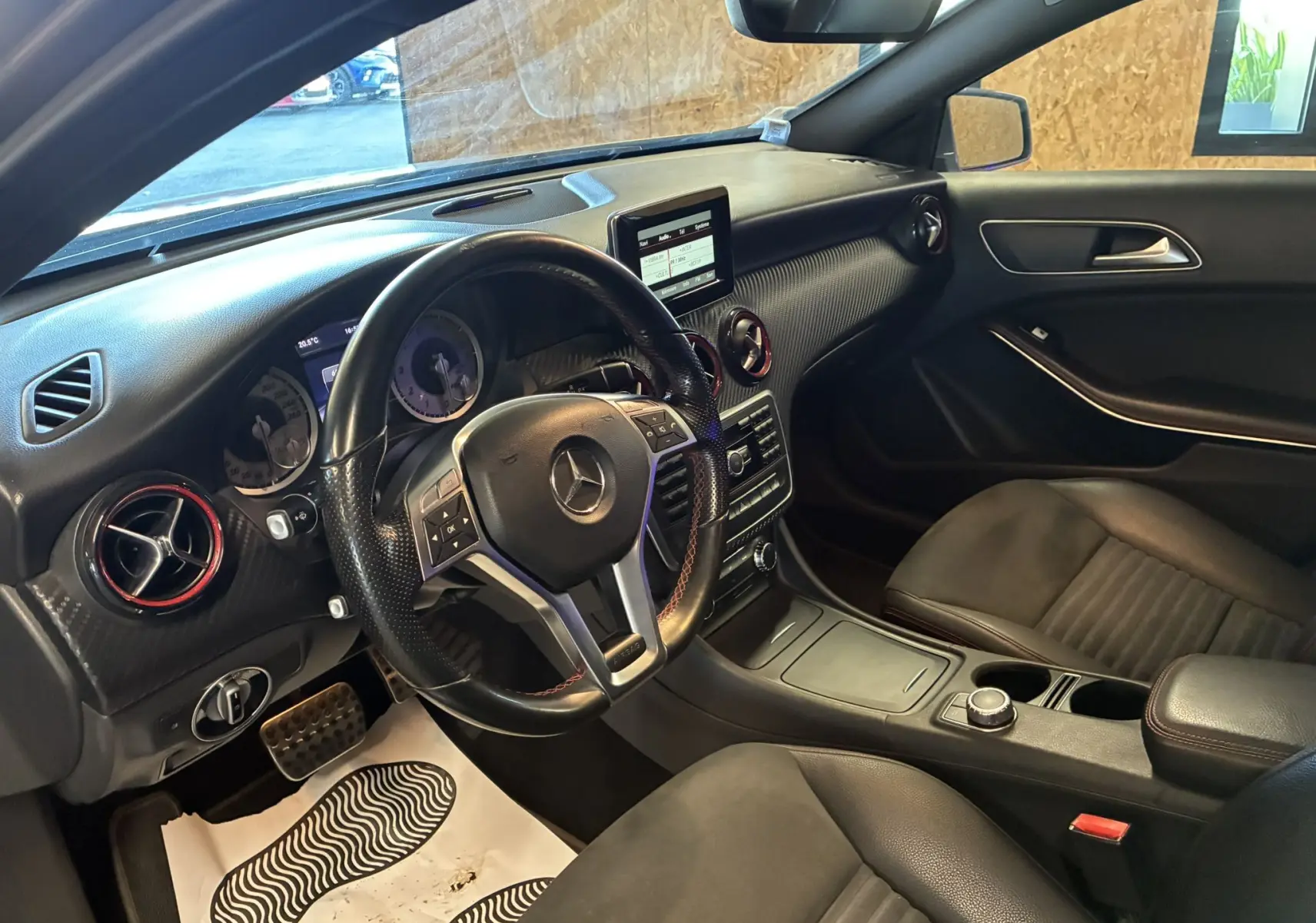 Intérieur noir de la Mercedes Classe A 250 AMG Sport 2014 vu côté conducteur, volant sport et tableau de bord moderne.