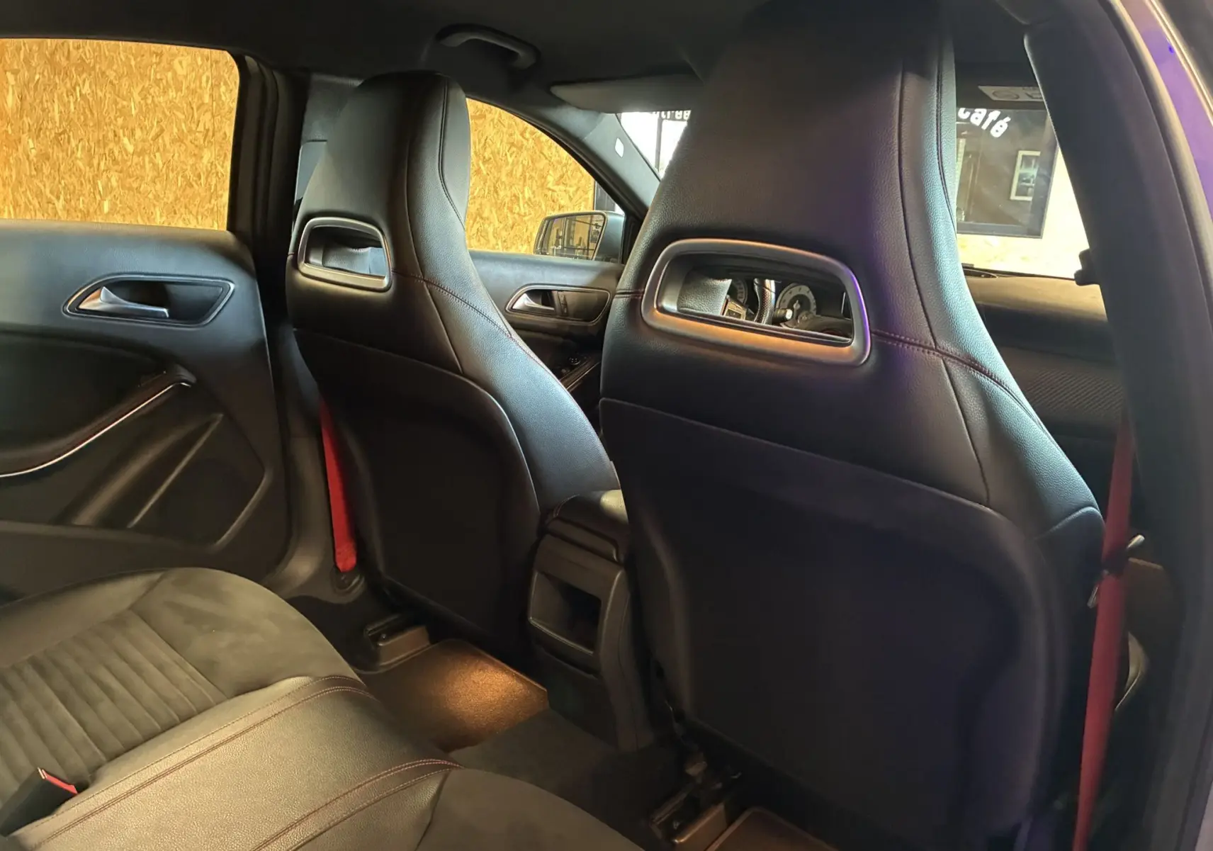 Vue intérieure arrière montrant les sièges avant en cuir noir et les garnitures de porte d'une Mercedes Classe A 250 AMG Sport gris.