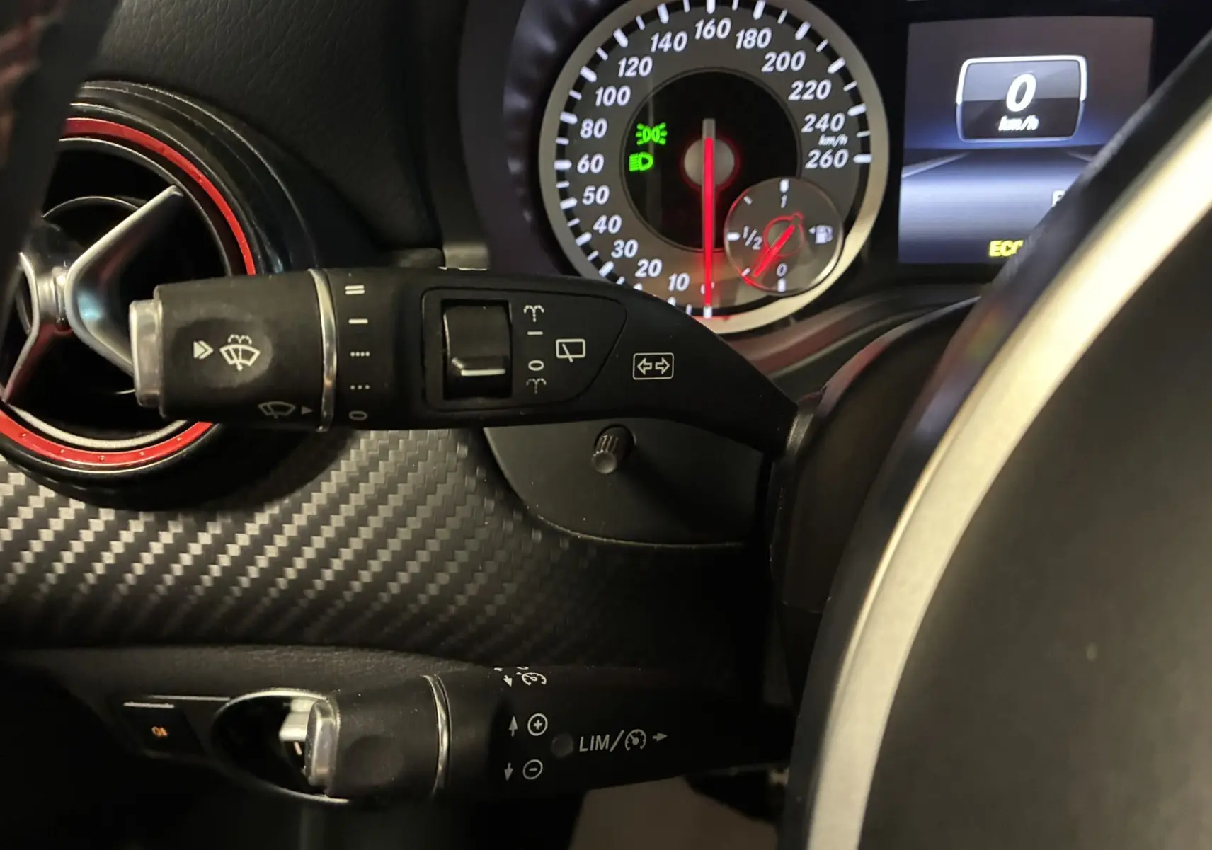 Gros plan sur le combiné d'instruments et les commandes au volant d'une Mercedes Classe A 250 AMG Sport gris, intérieur noir.