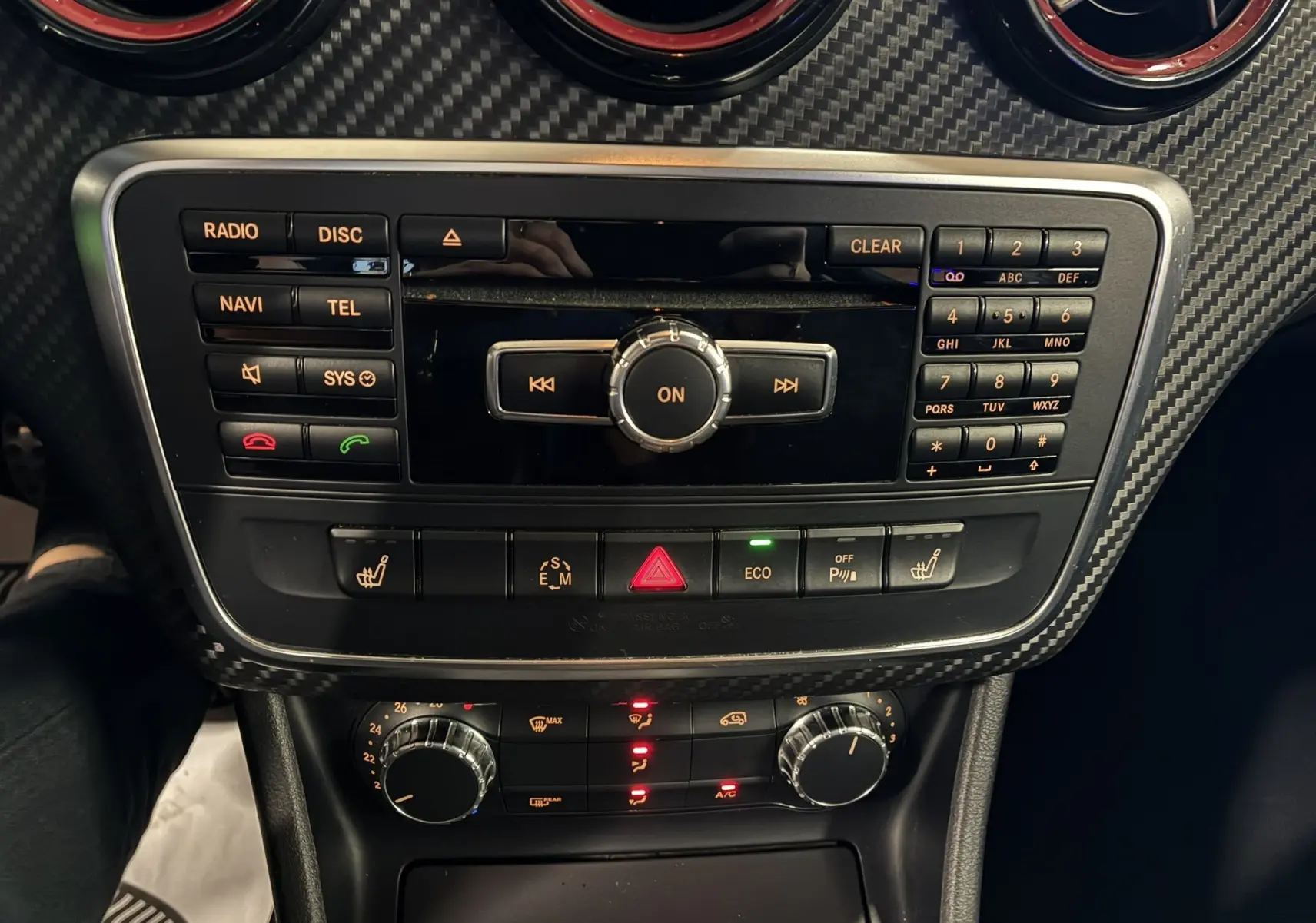 Console centrale de la Mercedes Classe A 250 AMG Sport 2014 avec commandes radio, climatisation et finition carbone noire.
