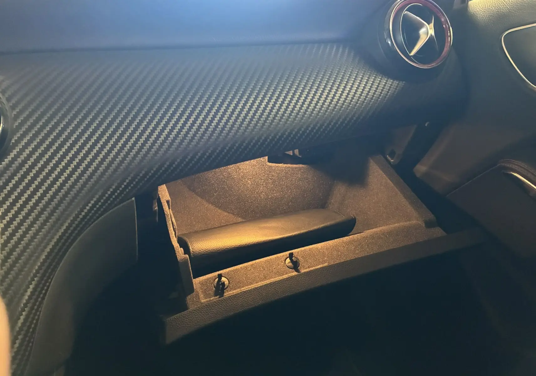 Intérieur de la Mercedes Classe A 250 AMG Sport 2014, boîte à gants ouverte sous tableau de bord gris à effet carbone.