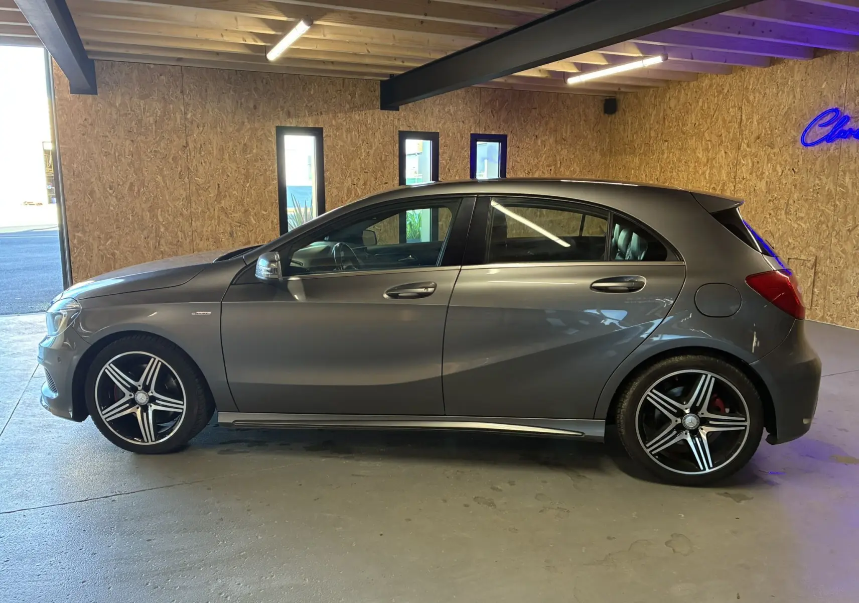 Vue de profil côté gauche d'une Mercedes Classe A 250 AMG Sport gris métallisé dans un garage en bois.
