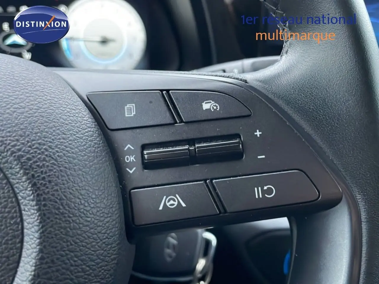 Gros plan sur les commandes de régulateur de vitesse au volant cuir noir de la Hyundai i20 Rouge Dragon Metal 2025.