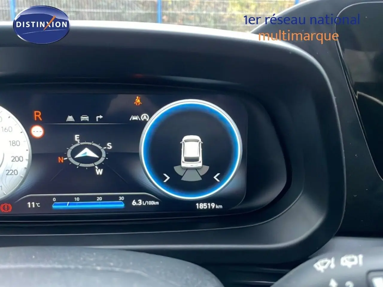 Gros plan sur le tableau de bord numérique de la Hyundai i20 2025 rouge Dragon Metal, affichant la consommation et le compteur kilométrique.