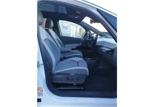 Vue intérieure côté conducteur du Volkswagen ID.3 blanc glacier, montrant les sièges avant et le tableau de bord moderne.