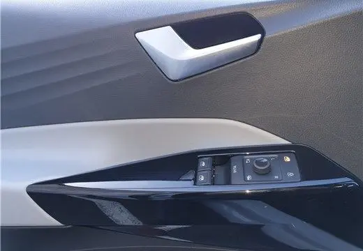 Détail de la porte côté gauche d'une Volkswagen ID.3 blanc glacier, montrant la poignée argentée et les commandes des vitres.