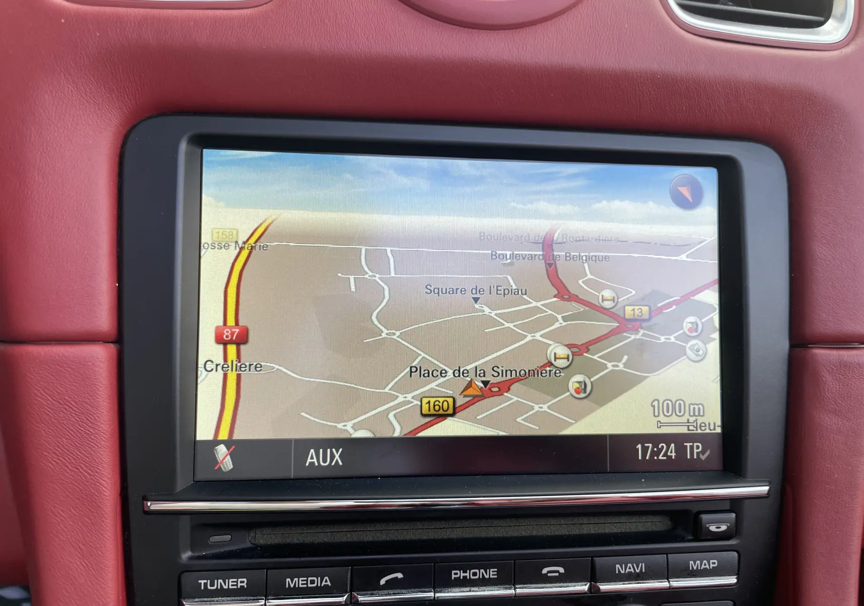 Écran de navigation allumé dans l'habitacle cuir rouge grenat d'une Porsche Boxster S 981 de 2012.