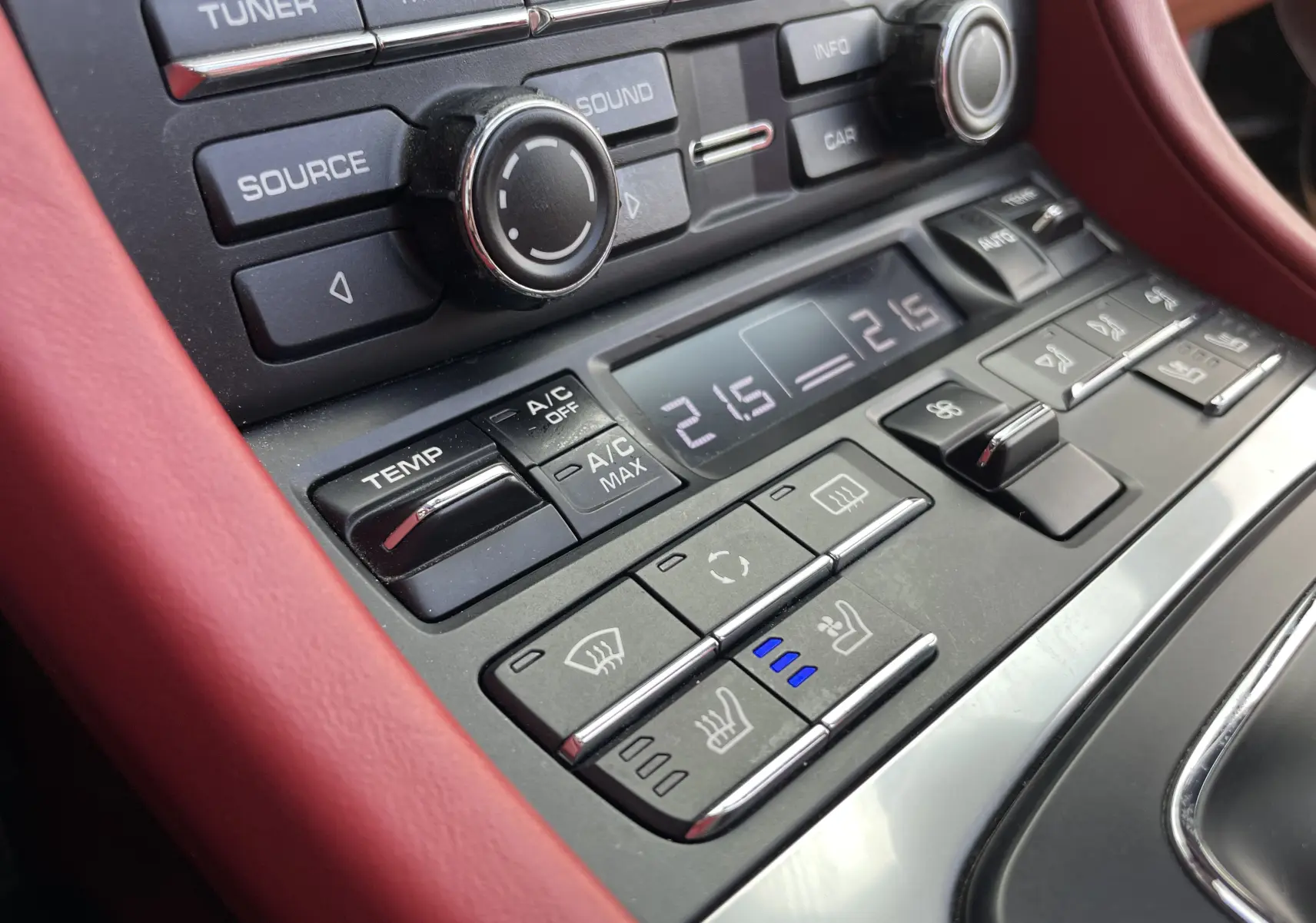 Gros plan sur la console centrale rouge grenat de la Porsche Boxster S 2012, avec commandes climatisation et sièges chauffants.