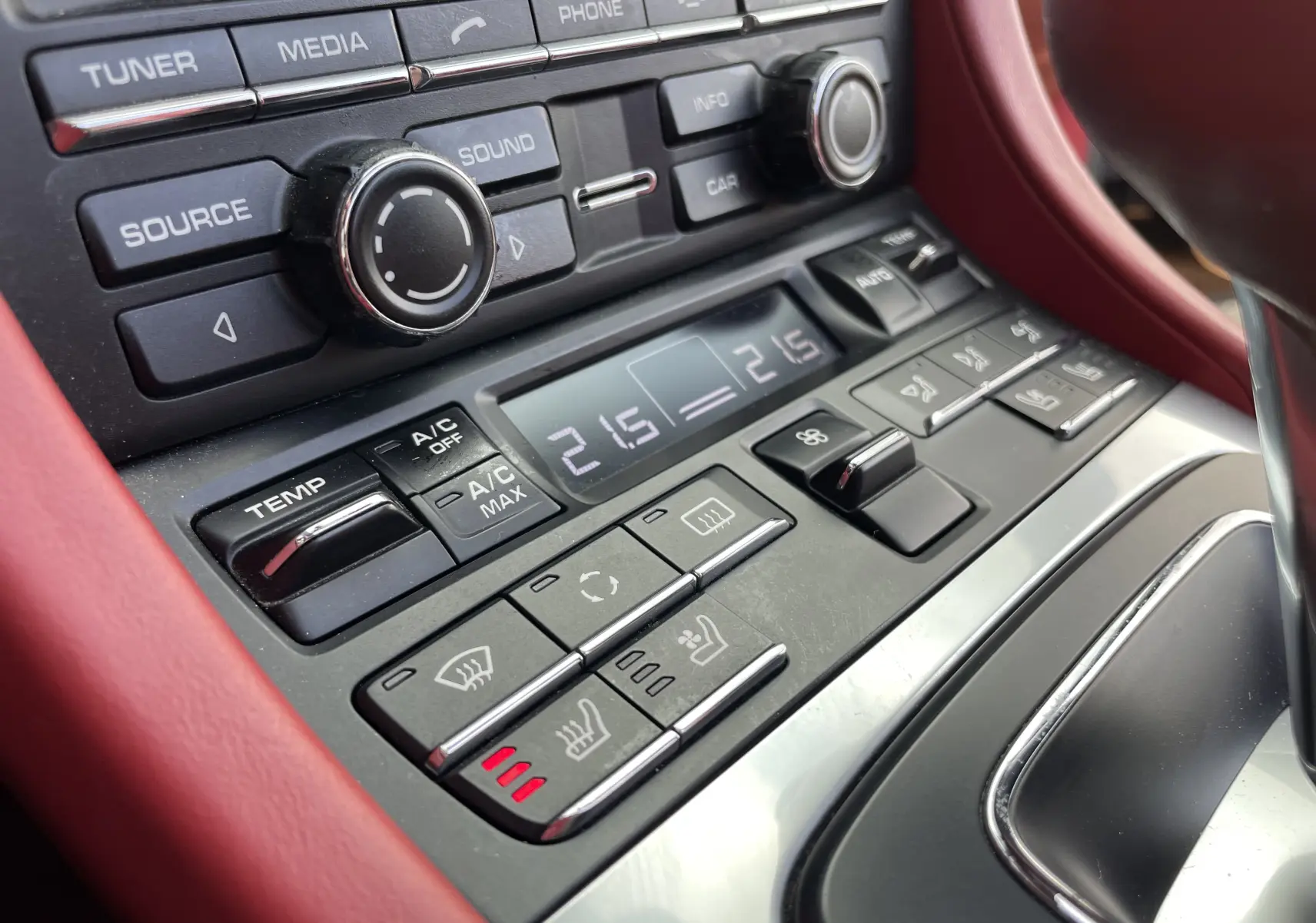 Gros plan sur la console centrale rouge grenat de la Porsche Boxster S 981 avec commandes climatisation et sièges chauffants.