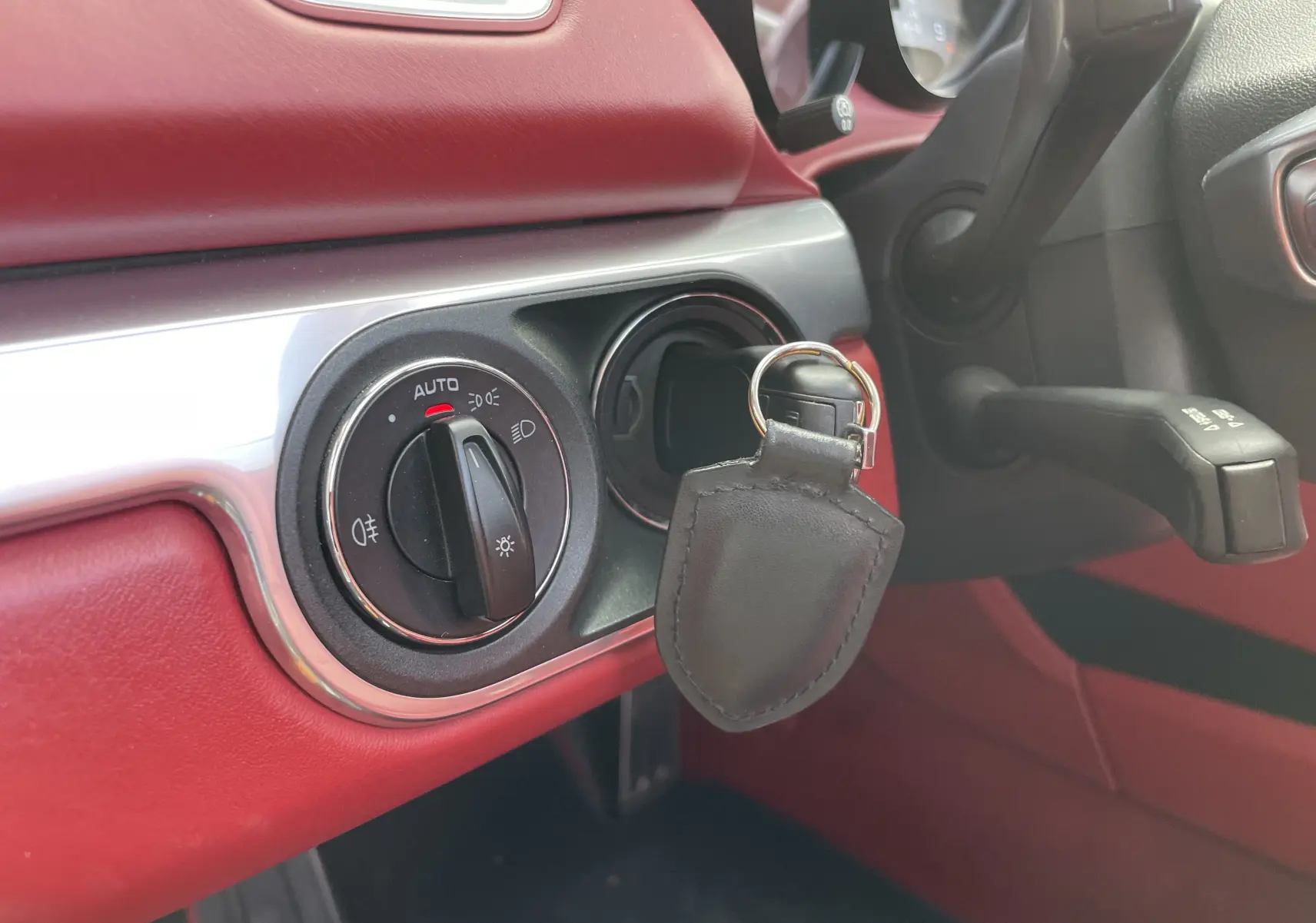 Détail du tableau de bord rouge grenat d'une Porsche Boxster S 981 avec commande d'éclairage et clé insérée.
