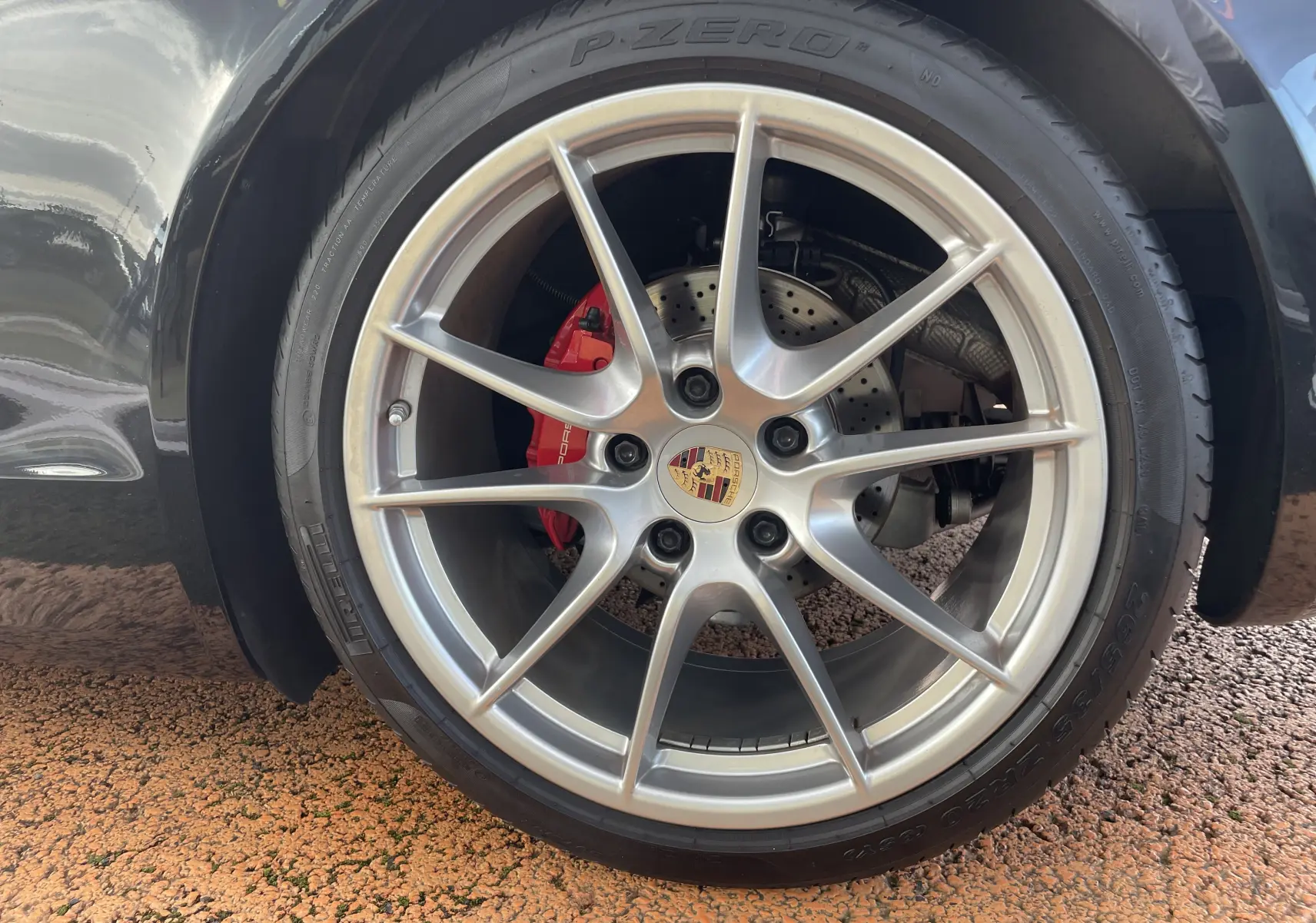 Gros plan sur la jante avant droite argentée et l'étrier de frein rouge de la Porsche Boxster S noir intense.