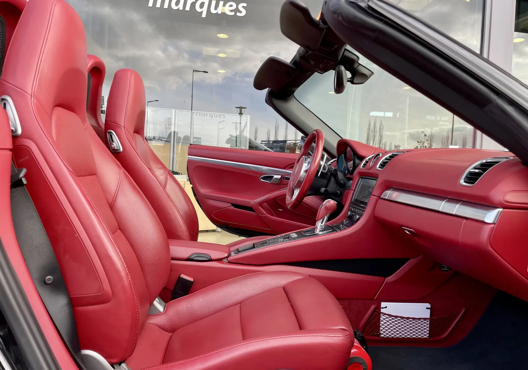 Intérieur rouge grenat de la Porsche Boxster S 981 2012 vue côté gauche avec sièges sport et tableau de bord détaillé.