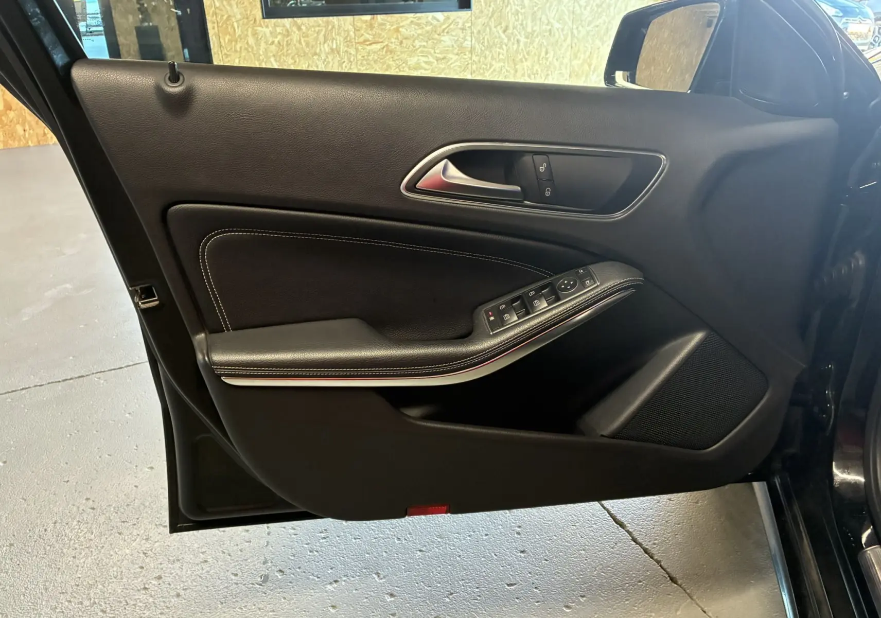 Vue intérieure de la porte avant gauche noire de la Mercedes Classe A 180 CDI Sensation avec commandes électriques et surpiqûres blanches.