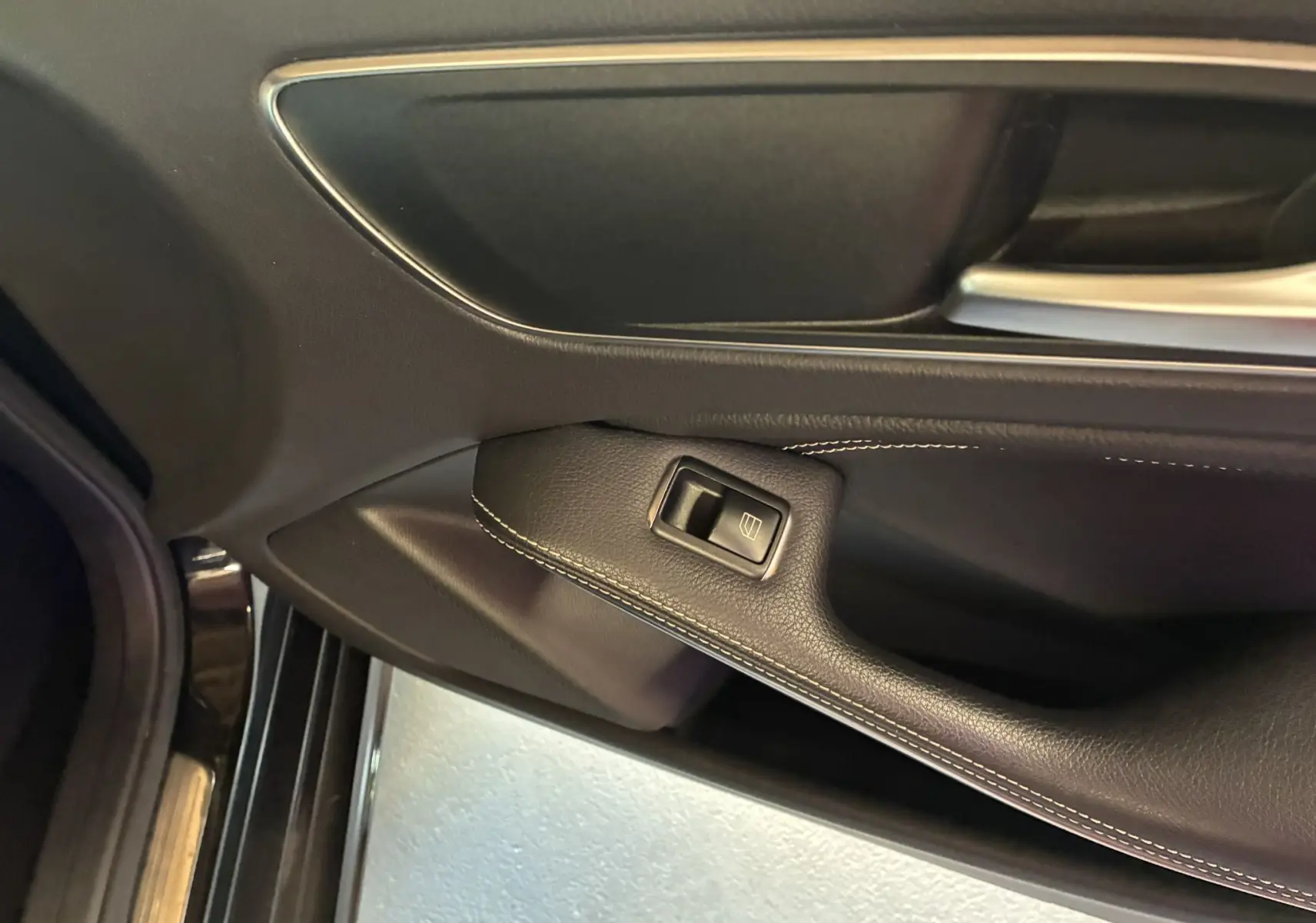 Gros plan sur la commande de lève-vitre côté conducteur de la porte noire intérieure d'une Mercedes Classe A 180 CDI Sensation 2018.