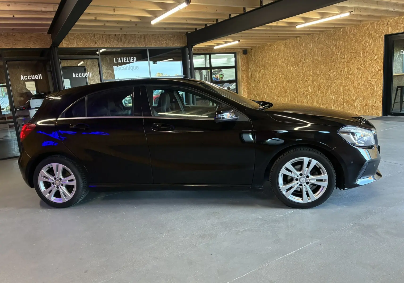 Profil côté gauche d'une Mercedes Classe A 180 CDI Sensation noire, en intérieur avec jantes alliage et vitres teintées.