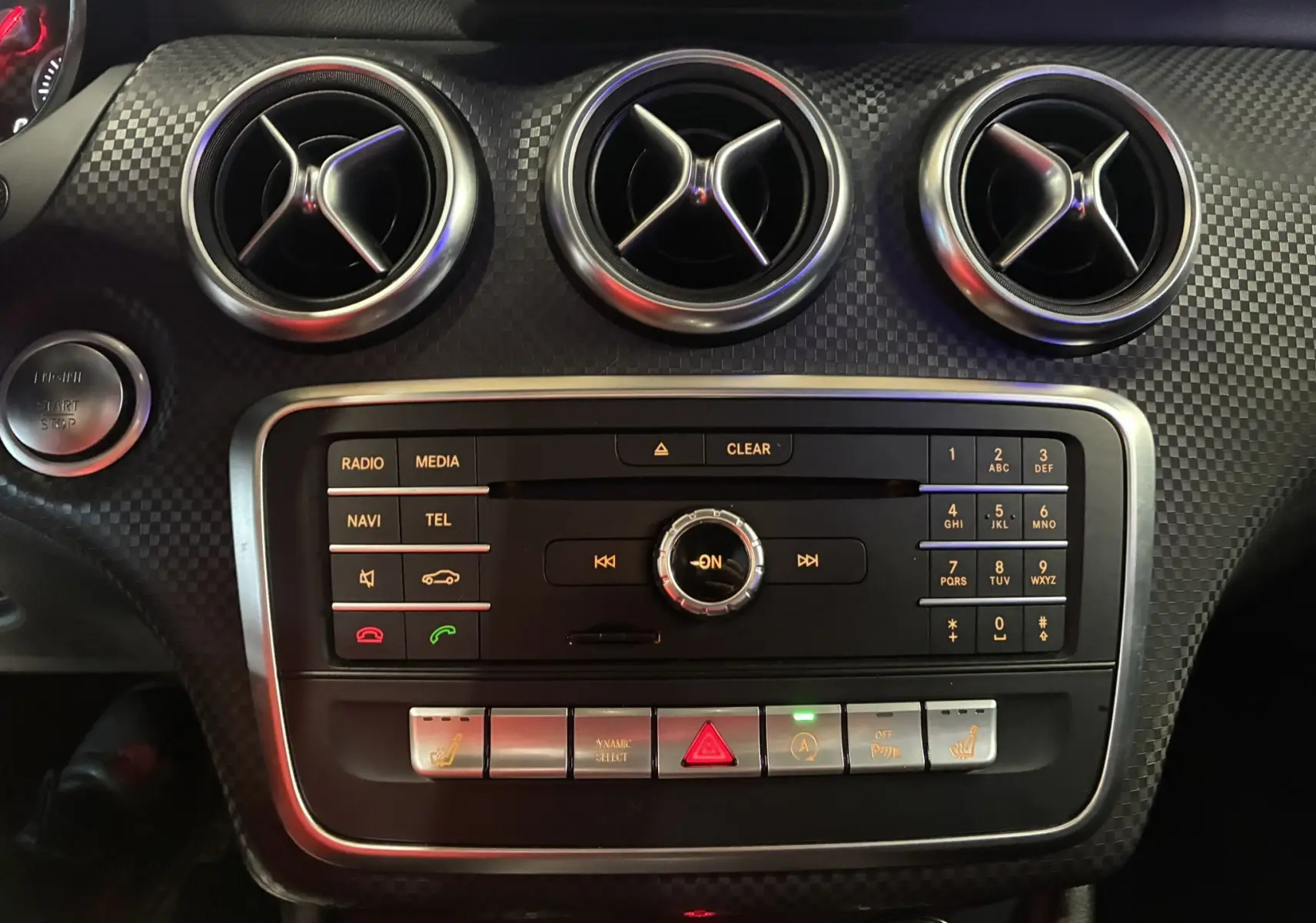 Tableau de bord noir de Mercedes Classe A 180 CDI 2018, vue rapprochée sur les aérateurs ronds et commandes centrales.