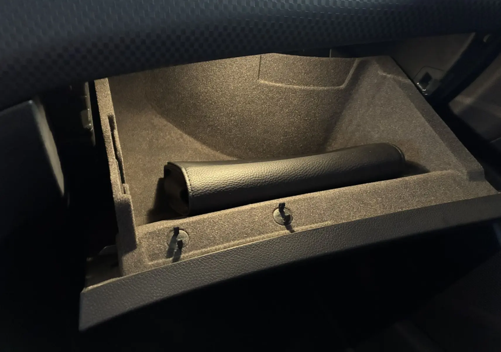 Gros plan sur la boîte à gants ouverte en tissu noir avec un étui en cuir noir dans une Mercedes Classe A 180 CDI Sensation 2018.