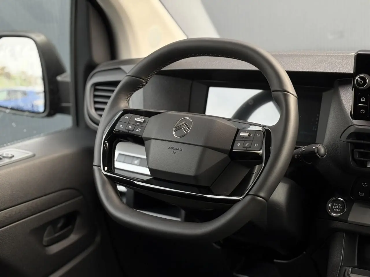 Vue intérieure centrée sur le volant cuir noir du Citroën Jumpy 2025 avec commandes intégrées et tableau de bord numérique.