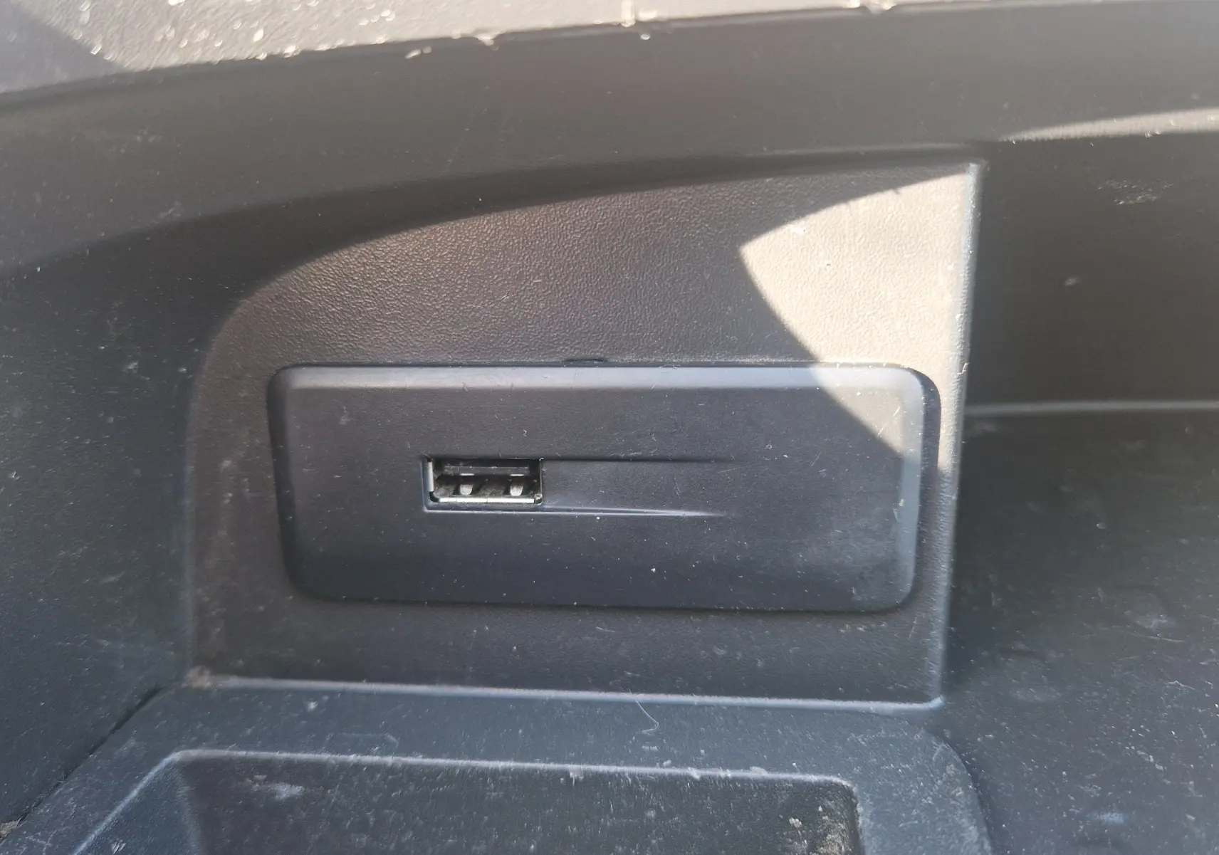Gros plan sur un port USB intégré dans la console intérieure noire du Renault Trafic Fourgon blanc.