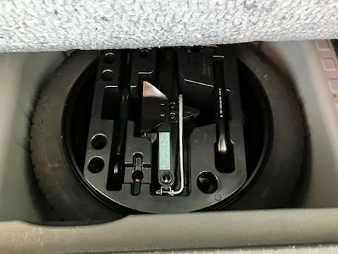 Gros plan sur la roue de secours et les outils de bord rangés sous le coffre du Renault Captur gris 2019.