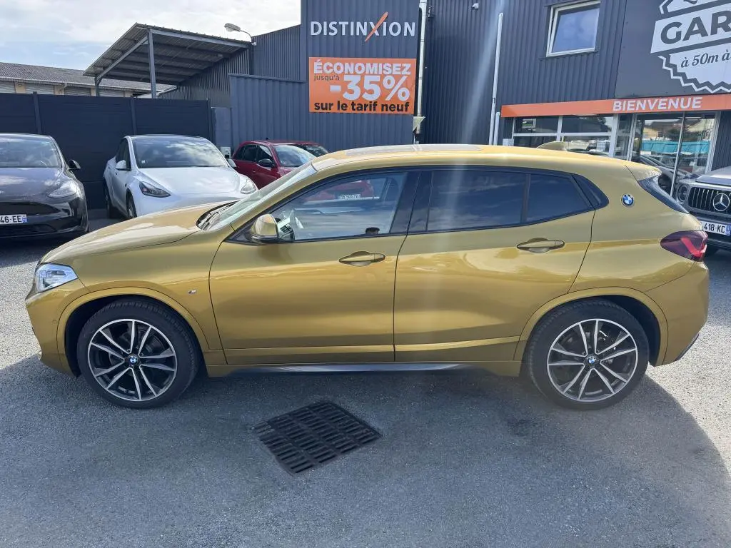 Profil côté gauche d'un BMW X2 jaune métallisé sDrive 18d M Sport avec jantes alliage 19 pouces et toit panoramique.