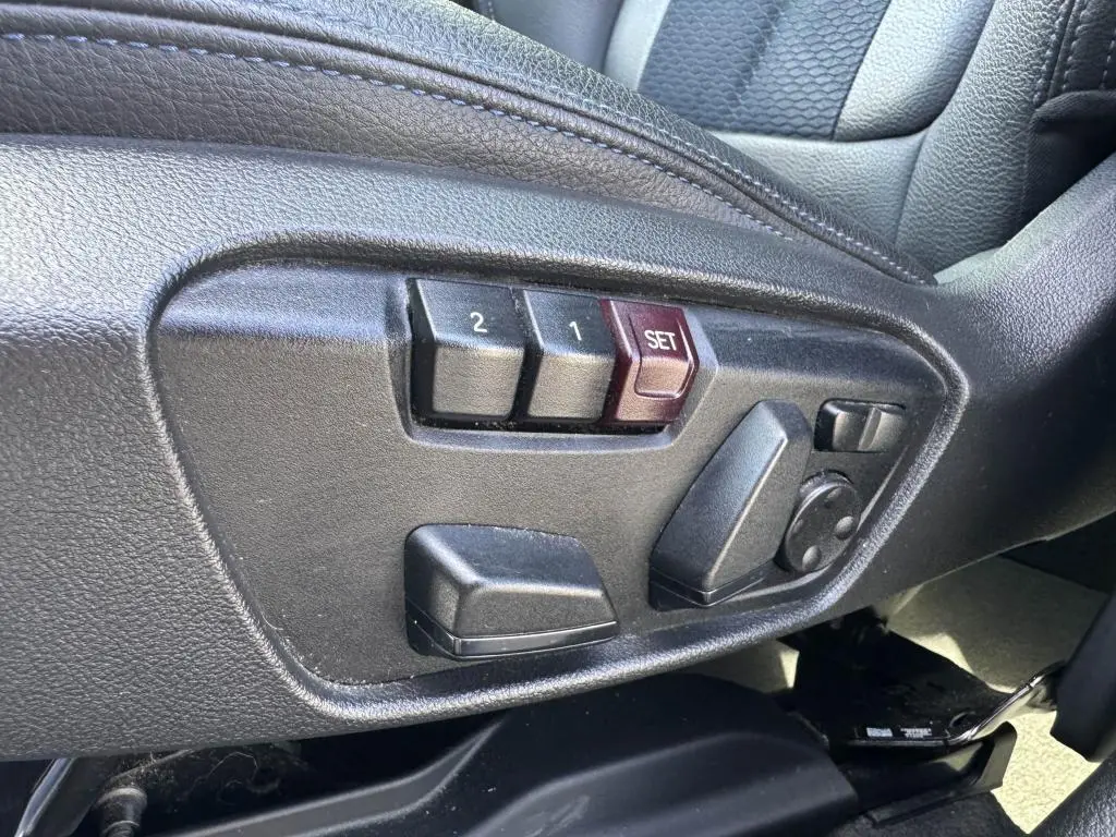 Gros plan sur les commandes électriques de réglage du siège conducteur noir du BMW X2 sDrive 18d M Sport 2021.
