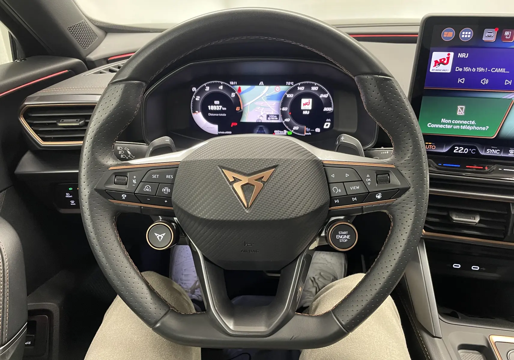 Vue intérieure centrée sur le volant CUPRA au design sportif avec tableau de bord numérique et écran tactile à droite.