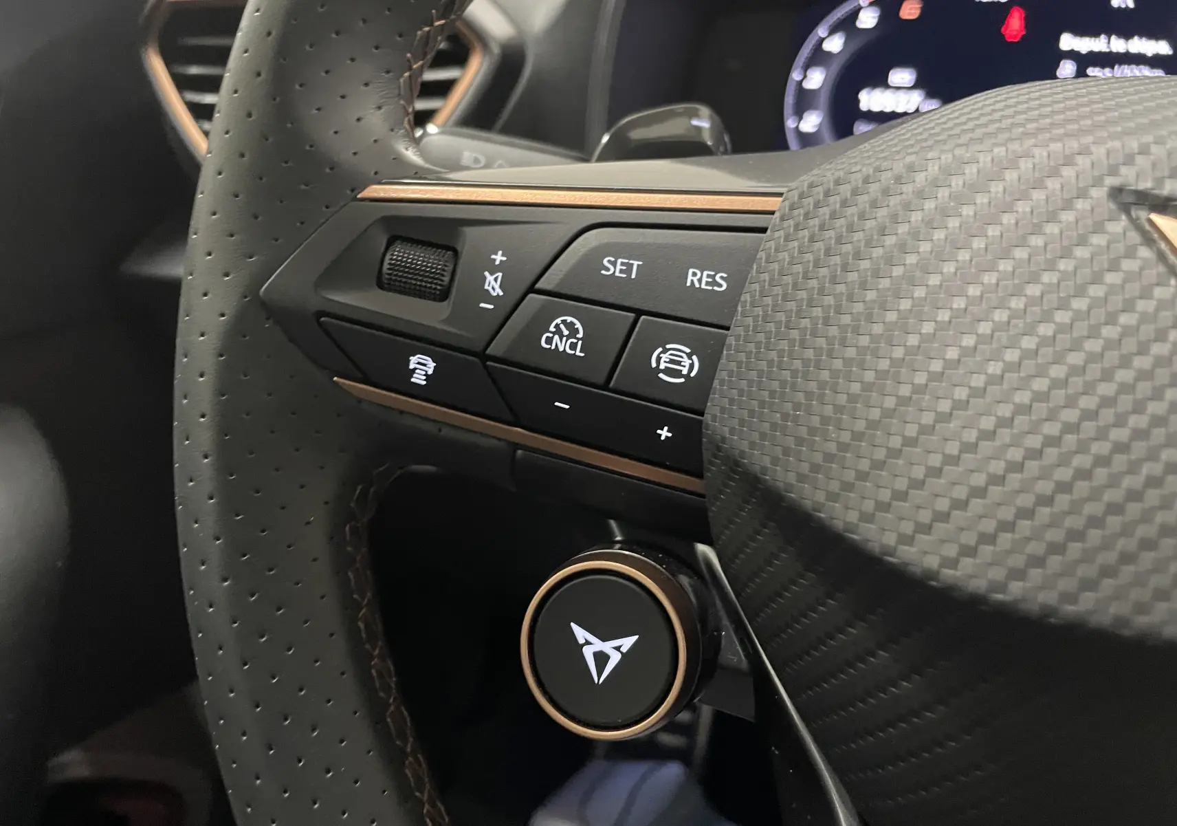 Gros plan sur le volant perforé du CUPRA Formentor 2025 avec commandes intégrées et logo lumineux au centre.