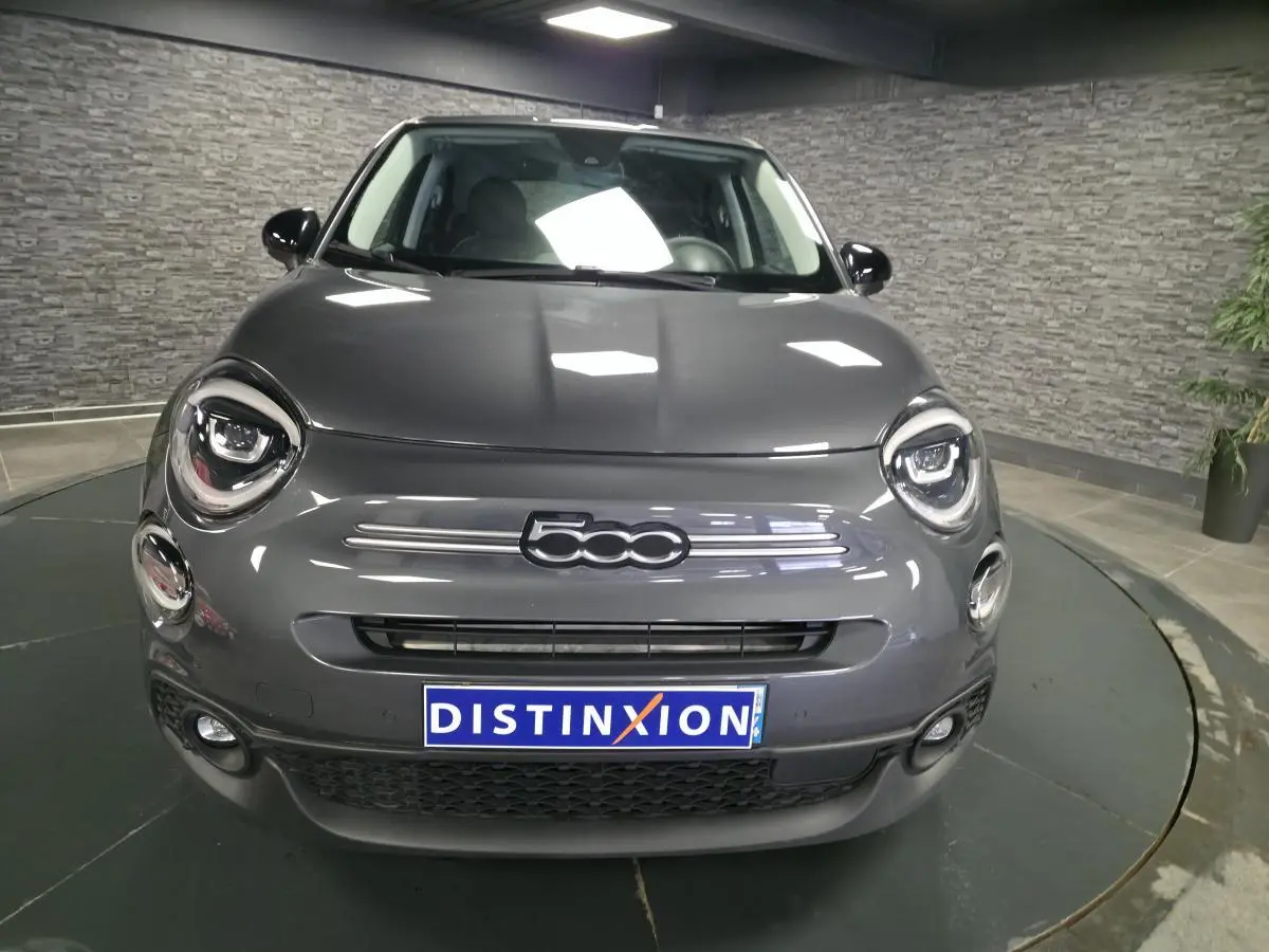 Vue de face d'une Fiat 500X gris métallisé avec phares LED et calandre épurée en intérieur showroom.