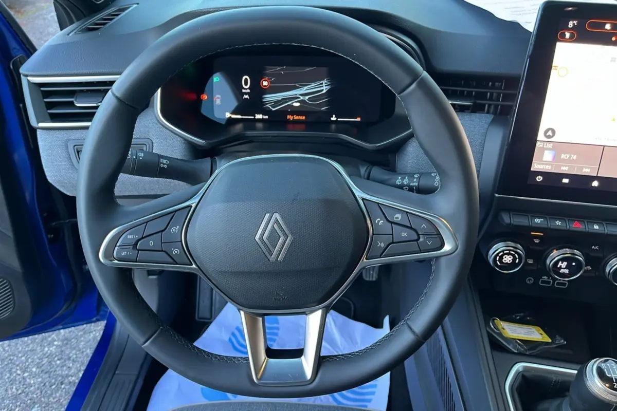 Vue rapprochée du volant cuir multifonctions et du tableau de bord numérique de la Renault Clio Bleu Iron 2025.