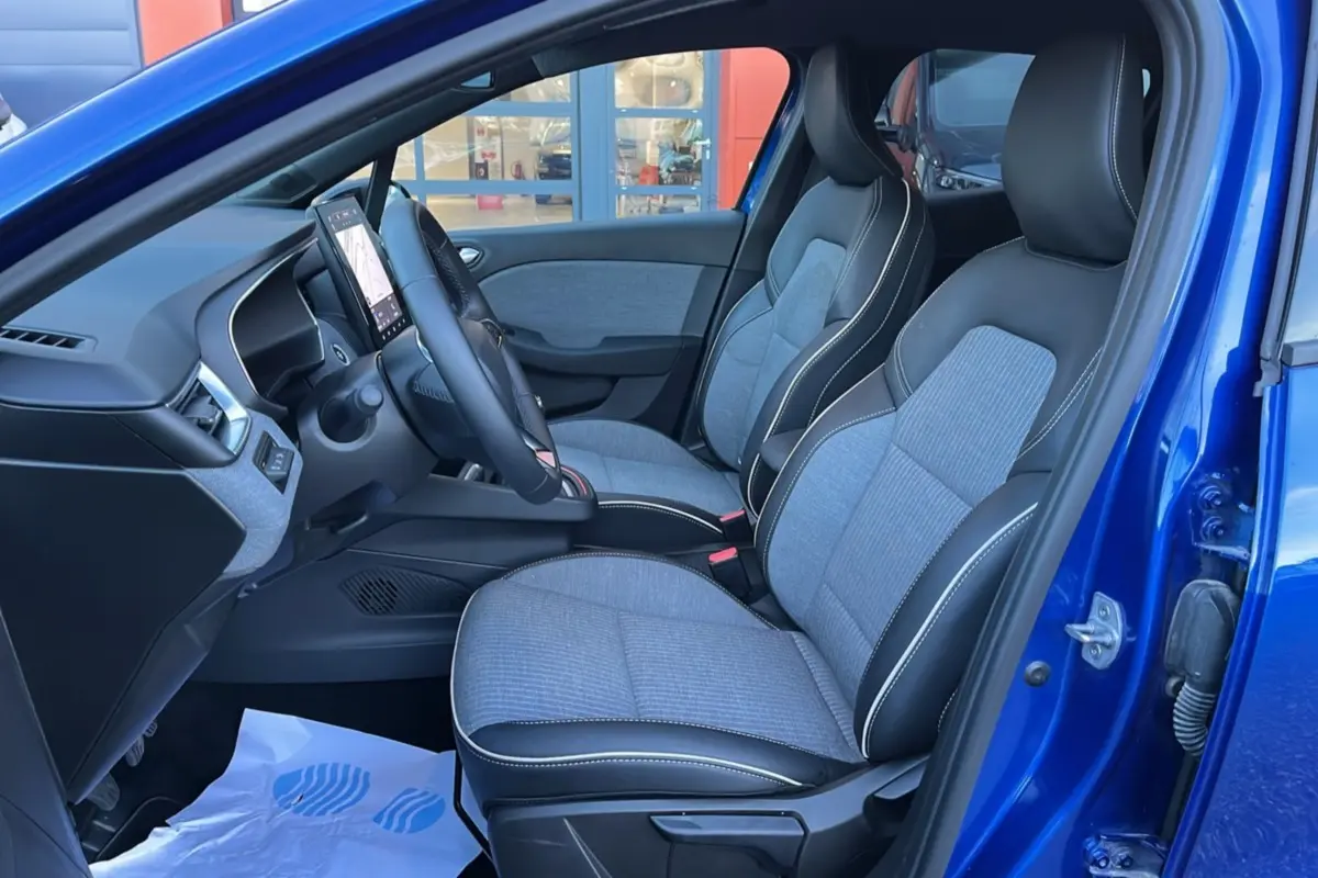 Intérieur avant droit de la Renault Clio 2025 bleu iron, sièges tissu gris et cuir noir avec surpiqûres blanches.
