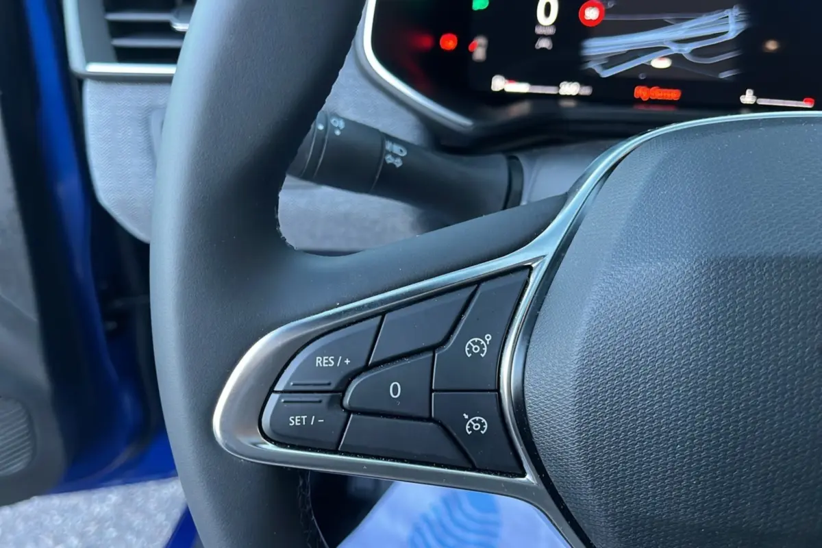 Gros plan sur les commandes de régulateur de vitesse au volant cuir d'une Renault Clio Bleu Iron 2025.