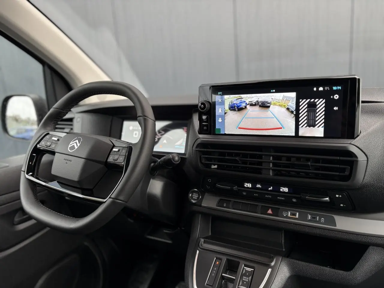 Intérieur du Citroën Jumpy XL 2025 vu côté conducteur, volant cuir et écran tactile affichant caméra de recul.